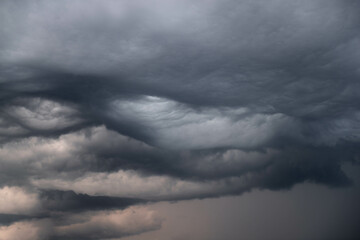 Czarne, ciężkie, pofałdowane burzowe chmury.  Budzą one grozę zapowiadając nadejście gwałtownych opadów i wiatru stanowiącego zagrożenie dla życia. - 526438798
