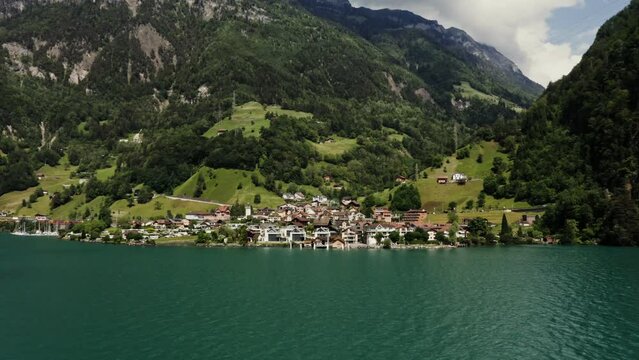 Scenic drone video, beautiful view of a modern village with a cottage development in a lowland between the Alpine mountains on the lake shore