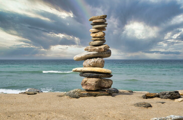 Fototapeta na wymiar stack of stones on the beach with rainbow