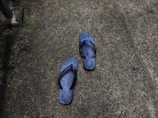 A pair of patterned black flip-flops on the cement floor.