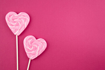 Pink lollipops and candies on a delicate background. Sweets and bonbons are a symbol of love. Top view flat lay with copy space