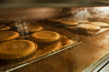 Oven baking pies pastries in a traditional European bakery kitchen, with baking tin, yellow orange colour theme