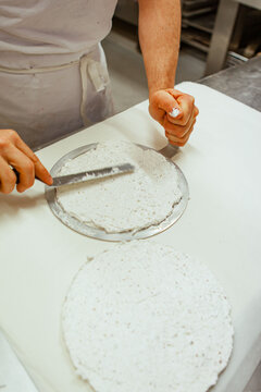 Traditional European bakery kitchen, patissier making cake to spead dacquoise cream base, palette knife with 6 Inch cake pan round base