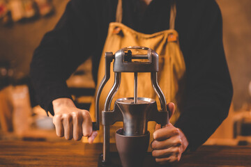 barista holding hand grinder to making beverage by grinding roasted coffee bean for caffeine drink in kitchen cafe background, morning breakfast mill preparation with espresso equipment in brown tone - obrazy, fototapety, plakaty