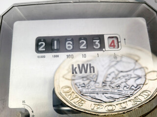 Electric power meter with pound coins overlaid - expensive fuel bills concept with multi-layered effect.