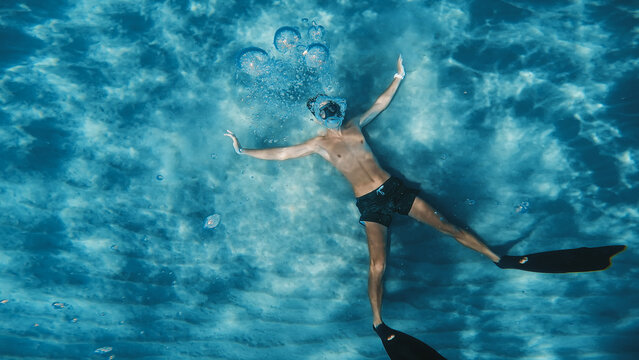 Young boy does freediving apnea underwater circular bubbles in the ocean