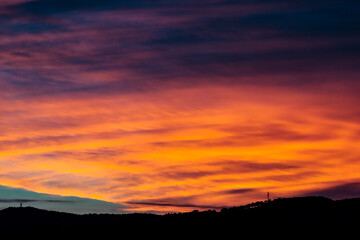 cloudy sunset with orange clouds and mountain silhouettes
