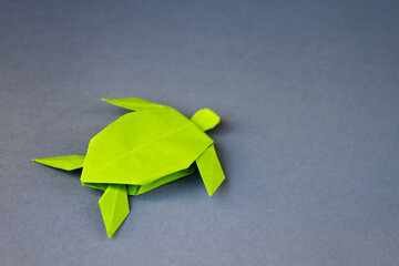 Green paper turtle origami isolated on a grey background