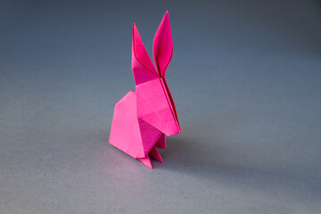 Pink paper rabbit origami isolated on a grey background