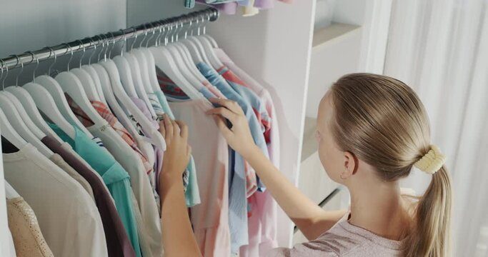A teenager chooses a dress in the dressing room. Top view