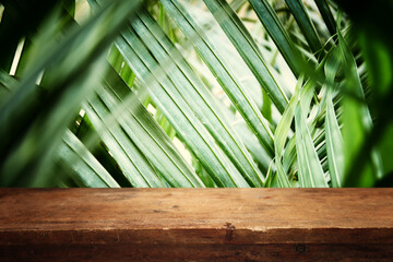 wooden table in front of tropical green floral background. for product display and presentation.