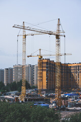 Construction tower cranes are installed on the construction site for the construction of a residential building.