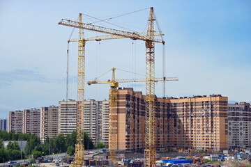 Fototapeta na wymiar Construction tower cranes are installed on the construction site for the construction of a residential building.
