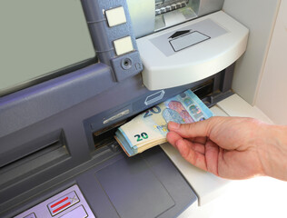 hand picking up Euros 20 banknotes on the ATM of the bank