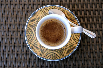 Top view into Americano Espresso coffee crema in fine bone china cup on rattan lounge table on ocean liner suite balcony veranda