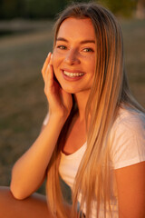 Fototapeta premium Close-up portrait of beautiful smiling female relaxing in the nature on warm sunny day