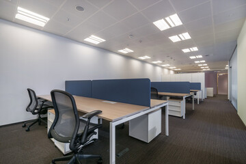 Modern office space with light walls, gray carpet and furniture.