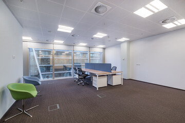 Modern bright office space with brown carpet, furniture and a large window.
