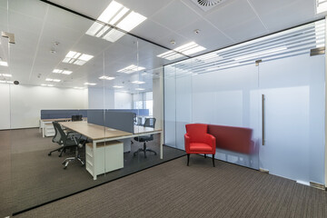Modern bright office with brown carpet, furniture and glass partitions.
