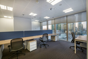 View of the open space of a modern office with gray carpet and furniture.