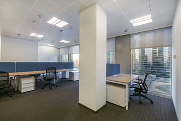 A spacious, bright office room with gray flooring and furniture.