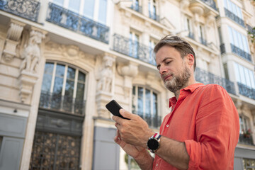 Caucasian man (businessman) using smartphone in the elegant street of Paris.