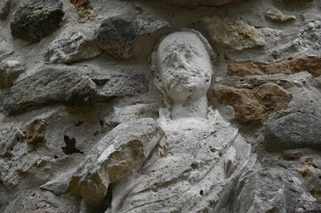 Verwitterte Frauenskulptur in einer rustikaln Sandsteinmauer
