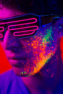 Fashion model with fluo painting on the face - Cool handsome young man with florescent creative make-up 