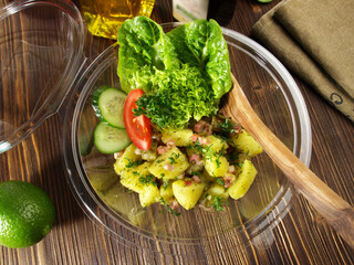 Potato Salad with Bacon in a Plastic Bowl on wooden Background - Take away