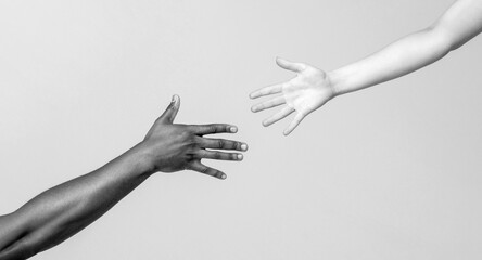 Helping hand, Rescue, multiathnic people. Helping hands, Rescue gesture. Giving a helping hand to another. Woman and african woman hand. African and caucasian hands. Black and white