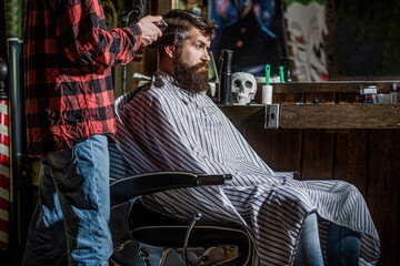 Hands of barber with hair clipper. Bearded man in barbershop. Haircut concept. Man visiting...