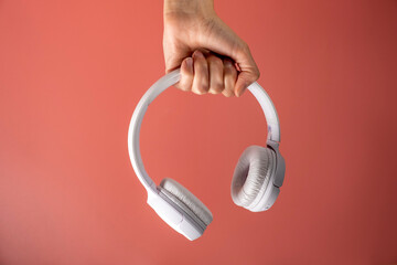Wireless white headphones background on the pink in woman's hand.