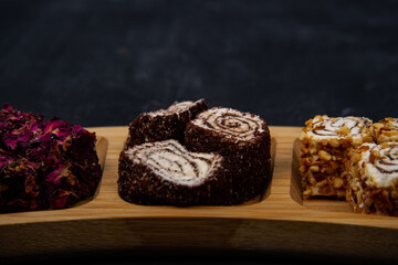 Turkish delight on wooden plate on black background