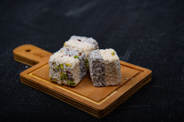 Turkish delight on wooden plate on black background