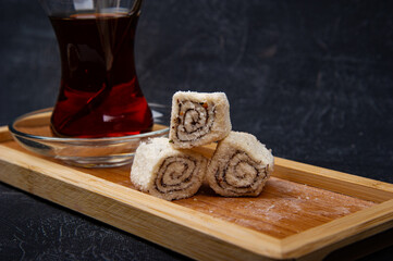 Turkish Delight and Turkish tea in wooden plate on black background