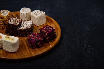Turkish delight on wooden plate on black background