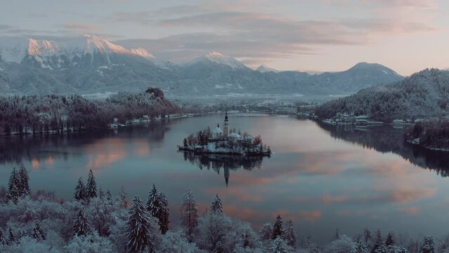 Amazing revealing shot of  Lake Bled, Slovenia on a beautiful golden morning in winter time. Snowy mountains in the background. Peaceful nature, fresh air, clean blue water. Top travel destination. Gr