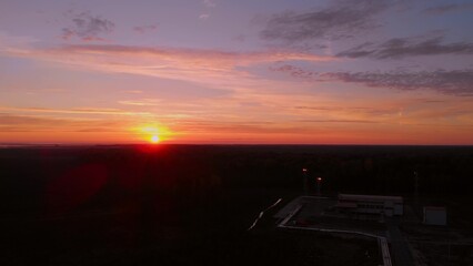 Red sunset over the taiga on the horizon the sun that illuminates the beginning day with bright rays. The drone flies over the dark horizons to the rays of the rising sun. Aerial view of sunrise.