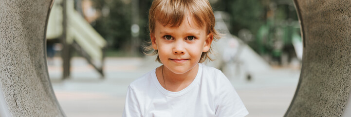 kid playing on city playground on ring around. cute little happy smiling candid five year old child...