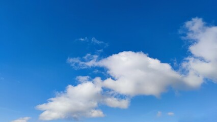 Light blue sky and clouds. In the light blue sky, rare clouds of bizarre shapes hang. Clouds are white fluffy as if stretching one after another.