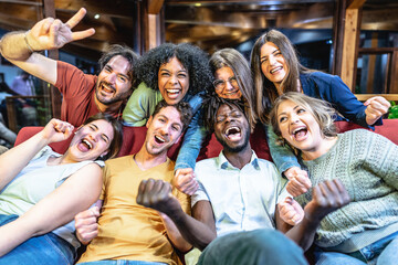 Fototapeta premium Multicultural best friends having fun on the couch while watching a football match- Room mates guys and girls enjoying time together in the university campus home