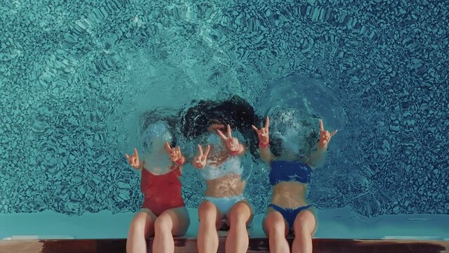 Three best friends enjoying their time at the blue swimming pool. They are having fun underwater. Summer party commercial.