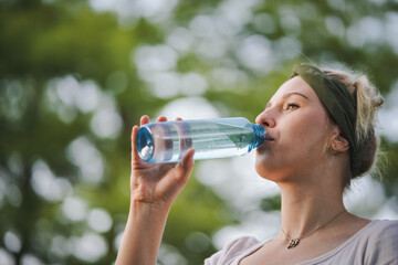 closeup o f a young healthy alternative & spiritual looking woman drinking fresh detox water from a...