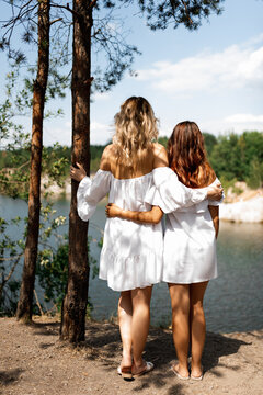mother and daughter in white sundresses walk in nature