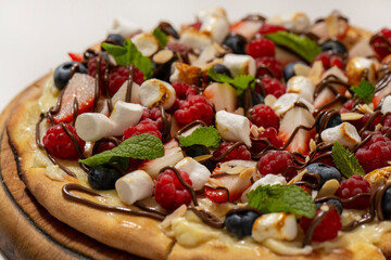 sweet pizza with berries and marshmallow on white background