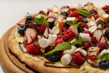 sweet pizza with berries and marshmallow on white background
