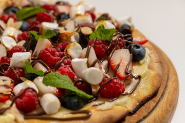 sweet pizza with berries and marshmallow on white background