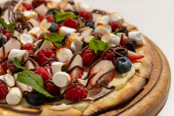 sweet pizza with berries and marshmallow on white background