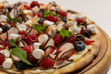 sweet pizza with berries and marshmallow on white background