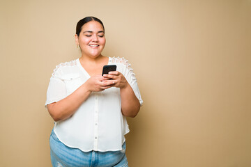 Excited plus size woman sending a text message on her smartphone